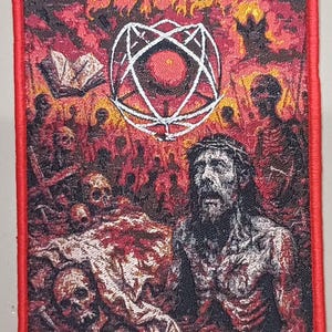May include: Embroidered patch with a red border featuring the band name "DEICIDE" above a central image. The image depicts a religious scene with a figure wearing a crown of thorns, surrounded by skulls and a hellish backdrop.
