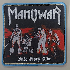 Peut inclure: Écusson carré avec un fond noir, portant le nom du groupe "Manowar" en lettres argentées scintillantes. L'écusson a une bordure bleue avec une garniture dorée et représente un groupe de personnages avec le texte "Into Glory Ride".