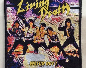 May include: A black and yellow embroidered patch featuring the band Living Death with the text "Watch Out!" in yellow. The band members are depicted in a colorful, stylized image.
