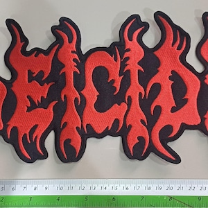 以下が含まれることがあります： 黒い背景に赤い炎のような刺繍で「DECAY」という文字が施された長方形のパッチ。パッチの長さは約25cmです。