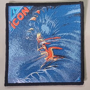 May include: A blue and orange embroidered patch with the word "ICON" in a white diamond shape. The patch features a stylised image of a person's face with a windblown hairstyle.