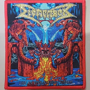 Puede incluir: Un parche bordado cuadrado con borde rojo que presenta un gráfico colorido de dos criaturas rojas similares a dragones flanqueando una calavera central, con el texto DISMEMBER arriba y LIKE AN EVER FLOWING STREAM abajo en azul y amarillo.