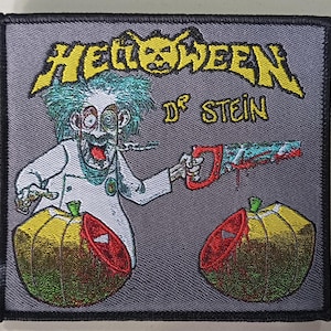 Puede incluir: Parche bordado con una imagen de dibujos animados de un científico loco con pelo verde sosteniendo una sierra ensangrentada, con el texto "Helloween Dr. Stein". El diseño incluye dos calabazas, una cortada. El parche tiene un fondo gris y un borde negro.