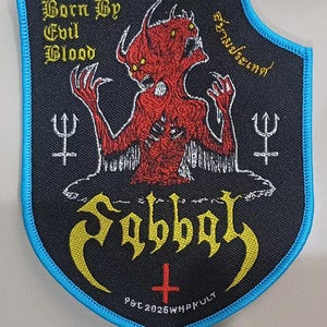Peut inclure: Un écusson brodé en forme de bouclier avec un fond noir et une bordure bleu vif. Il présente un démon rouge à deux têtes, du texte jaune indiquant Born By Evil Blood et Sabbat, une croix inversée rouge, des symboles de trident blancs et du texte.