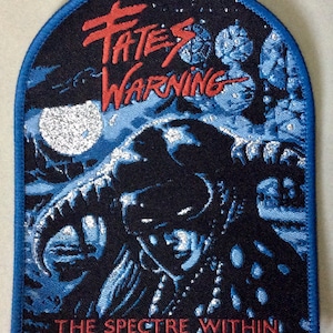 Puede incluir: Un parche bordado azul y negro con el texto "Fates Warning" en rojo y "The Spectre Within" en blanco. El parche presenta una figura oscura con cuernos y una luna plateada en el fondo.