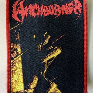 May include: A black and red embroidered patch with the band name "Wombbath" in red and the words "Incarnation of Evil" in yellow.