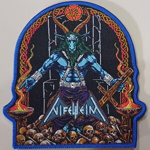 Könnte beinhalten: Gestickter Aufnäher mit einer blauen dämonischen Figur mit Hörnern, die ein Kreuz hält und von Schädeln und Flammen umgeben ist. Der Aufnäher hat einen blauen Rand und das Wort "Nifelheim" in einer stilisierten Schrift.