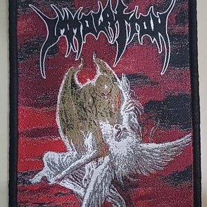 May include: Embroidered patch with a red and black background, featuring a winged figure and the text "Dawn Of Possession." The patch has a black border and white lettering. The design includes a detailed illustration.
