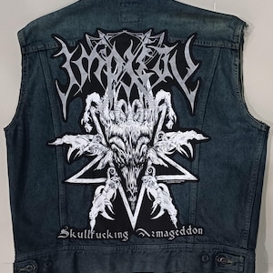 Puede incluir: Un chaleco vaquero azul descolorido con un parche grande en la espalda. El parche presenta una calavera de cabra blanca dentro de un pentagrama, con el texto "Skullfucking Armageddon" debajo. El chaleco es sin mangas.