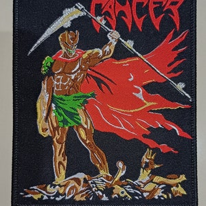 Op de afbeelding: Een zwarte geborduurde patch met een rode en witte figuur die een zilveren zeis vasthoudt. De figuur staat op een hoop botten. Het woord "CANCER" staat in rode letters bovenaan de patch.
