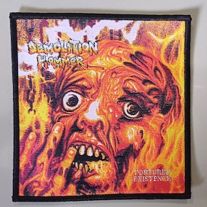 May include: A black and white patch with a red, orange, and yellow image of a face with the text "DEVOLUTION HAMMER" and "TORTURED EXISTENCE".