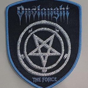 Puede incluir: Un parche bordado en forma de escudo con fondo negro y borde azul claro. Presenta la palabra Onslaught en una fuente estilizada en la parte superior, un pentagrama plateado dentro de un círculo en el centro y el texto THE FORCE en la parte inferior.
