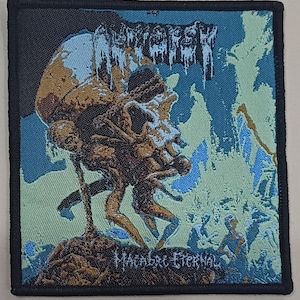 Könnte beinhalten: Quadratischer Aufnäher mit schwarzem Rand und detaillierter Illustration. Das Design zeigt einen Schädel mit Figuren und dem Text "MACABRE ETERNAL". Die Farbpalette besteht aus Braun-, Blau- und Grüntönen, wodurch ein dunkles und detailliertes Bild entsteht.