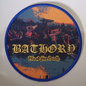 May include: Round patch with a blue border featuring the word "BATHORY" in gold gothic lettering, with "Blood fire Death" below. The patch has a dark blue background with an orange and red landscape design.