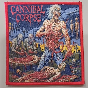 May include: Square patch with a red border featuring the text "CANNIBAL CORPSE" in red above a gruesome illustration. The image depicts zombies, gore, and a graveyard scene, with a blue background.