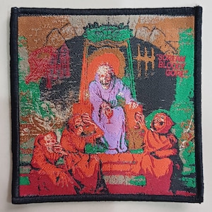 以下が含まれることがあります： 黒い縁取りと赤い刺繍が施されたパッチ。フードをかぶった人物が玉座に座り、その前にフードをかぶった人物が3人いる様子が描かれている。パッチの右上には「Scream Bloody Gore」の文字が見える。