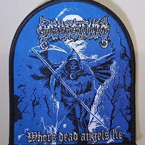 May include: A blue patch with a black border featuring a Grim Reaper figure with a scythe, a skull face, and a hooded cloak. The patch has the text "Where dead angels lie" in silver lettering. The top of the patch has a band name in silver lettering.