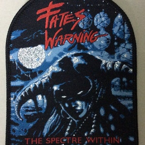 May include: A black embroidered patch featuring a silver and blue image of a creature with a crown. The text "FATES WARNING" is in red and "THE SPECTRE WITHIN" is in red at the bottom.