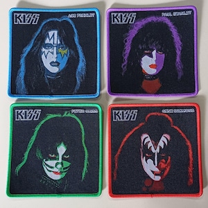 Puede incluir: Cuatro parches cuadrados con retratos de los miembros de la banda KISS: Ace Frehley, Paul Stanley, Peter Criss y Gene Simmons. Cada parche tiene un fondo negro con un borde colorido y el logotipo de KISS. Los retratos están maquillados.