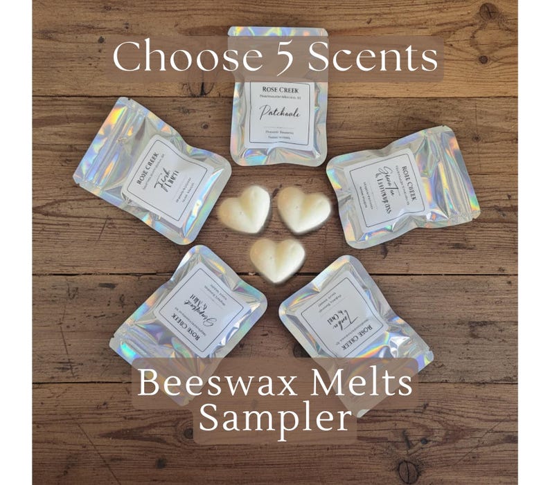 Op de afbeelding: Een bovenaanzicht van een houten oppervlak met vijf iriserende zakjes en drie hartvormige wassmelten. De zakjes zijn voorzien van het label "Rose Creek" en verschillende geurnamen. De tekst "Choose 5 Scents" en "Beeswax Melts Sampler" is ook zichtbaar.