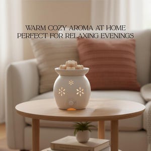 Op de afbeelding: Een witte keramische etherische olie diffuser met bloemvormige uitsparingen staat op een ronde houten tafel. De diffuser is bedekt met wax melts. De tekst op de afbeelding luidt: "WARM COZY AROMA AT HOME PERFECT FOR RELAXING EVENINGS."