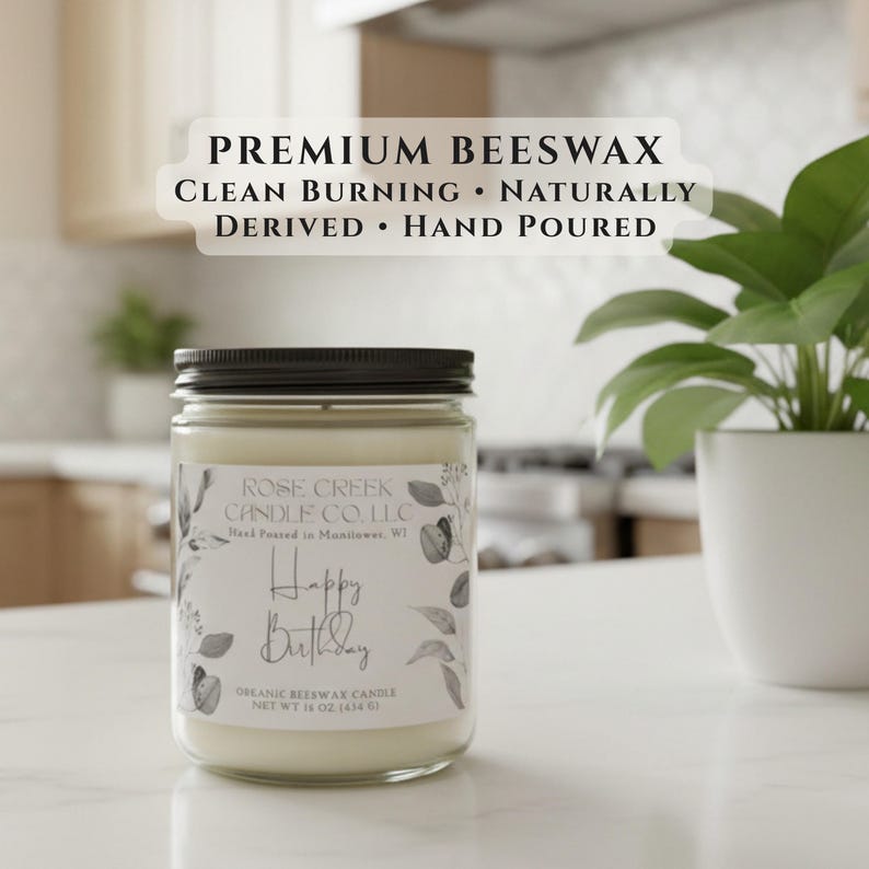 May include: A 16 oz. beeswax candle in a clear glass jar with a black lid. The label reads PREMIUM BEESWAX CLEAN BURNING NATURALLY DERIVED HAND POURED, ROSE CREEK CANDLE CO. L.L.C, Happy Birthday, and NET WT 16 OZ. (454 G) with botanical illustrations.