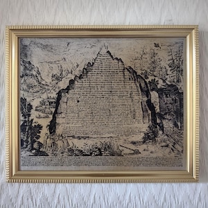 Könnte beinhalten: Ein gerahmter Schwarz-Weiß-Druck mit einem goldenen Rahmen. Der Druck zeigt einen Berg mit Text und eine Landschaftsszene. Das Kunstwerk hat eine Vintage-Ästhetik mit detaillierten Illustrationen von Bäumen, Figuren und Gebäuden.