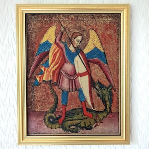 Op de afbeelding: Een ingelijst schilderij met een gevleugelde figuur in roze en blauw harnas die een lange speer en een wit schild met een rood kruis vasthoudt, staand over een groene draak. Het kunstwerk heeft een textuurrijke rode achtergrond.