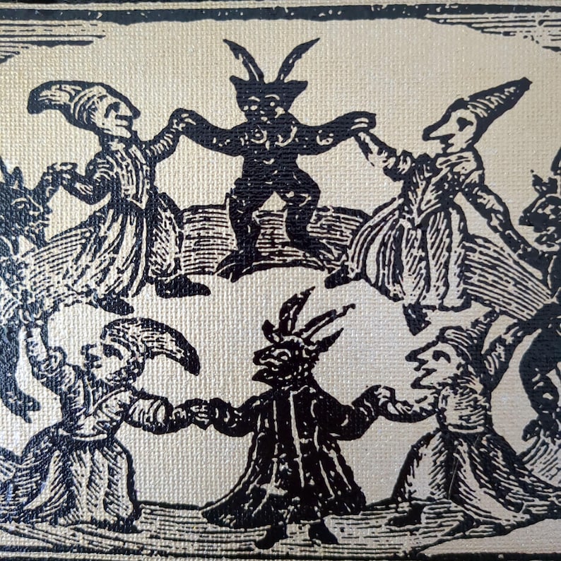 May include: Black and white illustration of figures dancing in a circle. The figures include horned demons and people in long robes and hats, all holding hands. The artwork has a vintage, antique aesthetic.