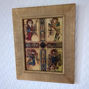 Peut inclure: Une &oelig;uvre d'art encadr&eacute;e avec quatre panneaux repr&eacute;sentant des anges. Le cadre dor&eacute; a une surface textur&eacute;e et une bordure en forme de corde. Les illustrations d'anges sont de diff&eacute;rentes couleurs, dont le rouge, le bleu et le jaune. C'est une pi&egrave;ce d&eacute;corative.