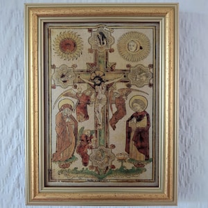 Könnte beinhalten: Gerahmtes religiöses Kunstwerk mit einer zentralen Kreuzigungsszene mit Figuren und Engeln. Das Kunstwerk hat einen goldfarbenen Rahmen. Das Bild enthält Sonnen- und Mondsymbole sowie Figuren in Gewändern. Das Kunstwerk ist im Vintage-Stil.