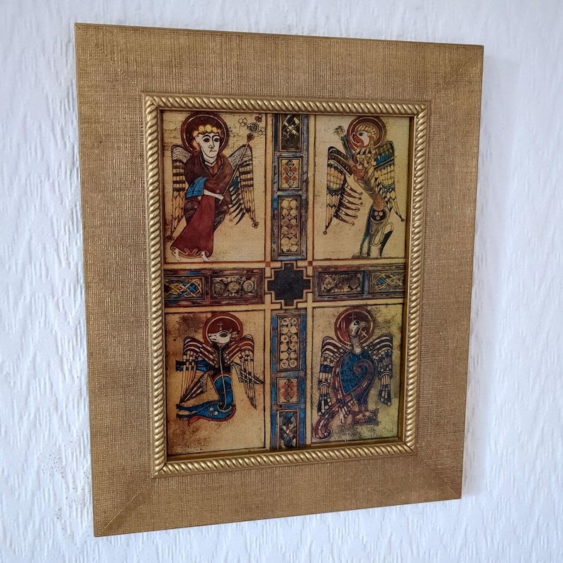 Peut inclure: Une &oelig;uvre d'art encadr&eacute;e repr&eacute;sentant quatre illustrations d'anges avec des ailes, des aur&eacute;oles et des robes rouges, bleues et jaunes. L'&oelig;uvre est encadr&eacute;e dans un cadre dor&eacute; avec une bordure marron clair textur&eacute;e.