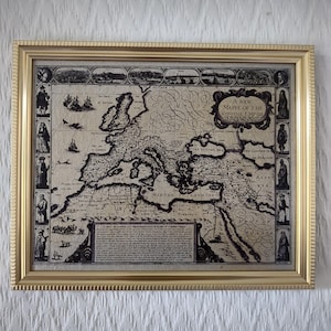 Op de afbeelding: Een ingelijste zwart-witte kaart van het Romeinse Rijk met de titel "A New Mappe of the Romane Empire". De kaart toont de grenzen van het Romeinse Rijk, inclusief de Middellandse Zee, de Zwarte Zee en de Kaspische Zee. De kaart is omgeven door een gouden lijst.