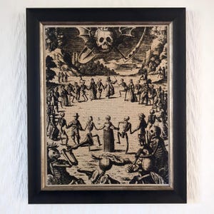 May include: Black framed print depicting a macabre scene of skeletons dancing in a circle, with a skull and scythe above. The artwork is in a vintage style, with detailed figures and a beige background.
