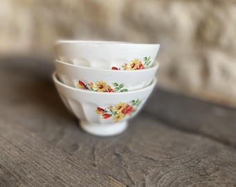 Drie middelgrote café au lait kommen, wit met rode en gele bloemen