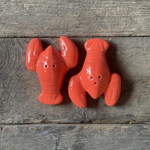 Röda salt- och pepparkar i keramik, formade som två humrar