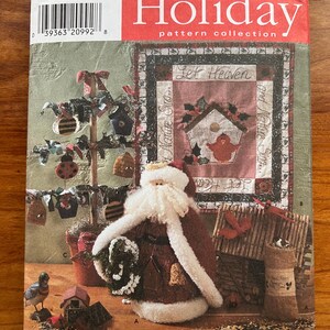 Może przedstawiać: Kolekcja wzorów Simplicity Holiday z lalką Świętego Mikołaja, budką dla ptaków, choinką i blokiem patchworkowym z tekstem "Let Heaven and Nature Sing".