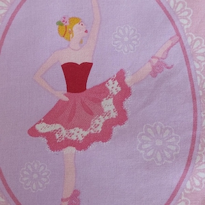 May include: A pink fabric panel featuring a central oval frame with a white lace border. Inside, a blonde figure in a red bodice and pink tutu performs a ballet pose. The word Ballet is printed in script above the figure, surrounded by floral motifs.