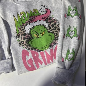 May include: Gray sweatshirt with a pink "Mama Grinch" graphic featuring the Grinch wearing a Santa hat and a leopard print background. The sleeves have pink hearts with the names "Alex", "Anthony", "Young", and "Kai" written inside.