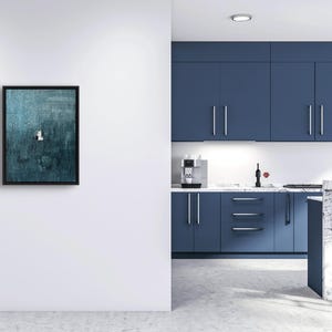 May include: A rectangular wall art piece featuring a dark teal and blue textured abstract painting enclosed in a thin black frame. The artwork displays a small, centered white and black geometric accent against the deep, layered blue background.