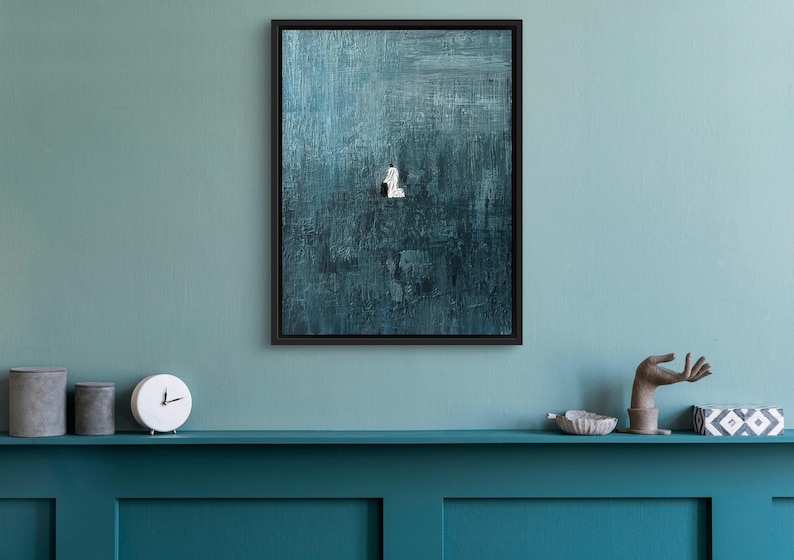 May include: A framed rectangular wall art piece featuring a deep teal and dark blue textured background with visible brushstrokes. In the center, a small, solitary white figure stands against the vast, dark, and moody painted surface.