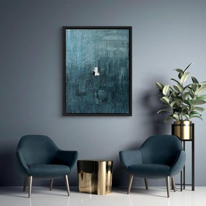 May include: A rectangular wall art piece featuring a dark teal and blue textured background with a small, centered white figure. The artwork is enclosed in a thin black frame, showcasing visible brushstrokes and a deep, moody color palette.