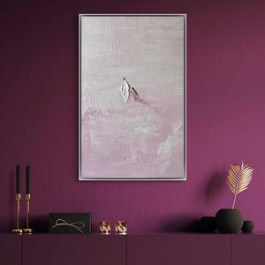 Pode incluir: Pintura abstrata emoldurada em prata. A obra apresenta um fundo rosa claro texturizado com pinceladas brancas e roxas. Uma forma de folha branca e uma linha roxa est&atilde;o no centro.