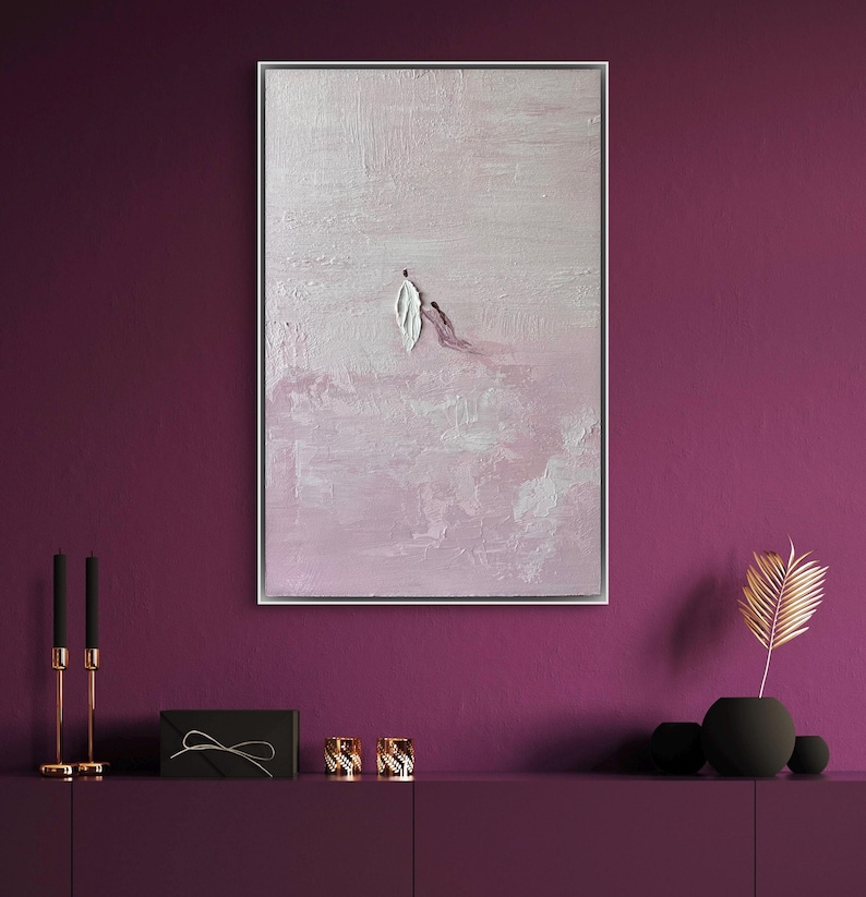 Pode incluir: Pintura abstrata emoldurada em prata. A obra apresenta um fundo rosa claro texturizado com pinceladas brancas e roxas. Uma forma de folha branca e uma linha roxa est&atilde;o no centro.