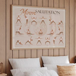 May include: A rectangular wall poster titled Moon Salutation featuring a series of brown-toned illustrations depicting various yoga poses arranged in a grid, framed in a light-colored wooden frame and displayed on a vertical wood-paneled wall.