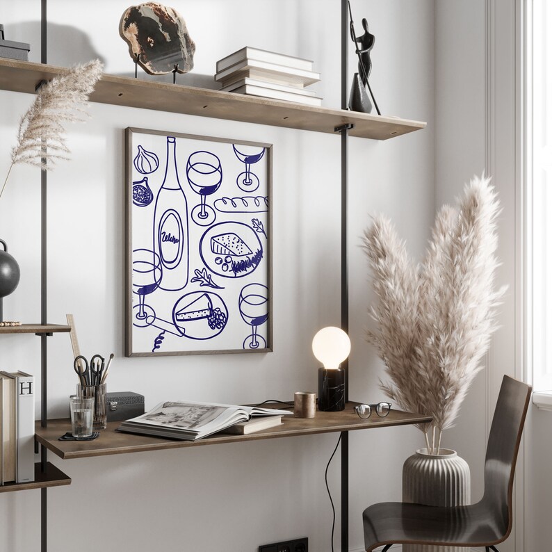 May include: A framed illustration of a bottle of wine, glasses, cheese, and bread. The illustration is in blue on a white background. The frame is black and the illustration is hanging on a white wall.