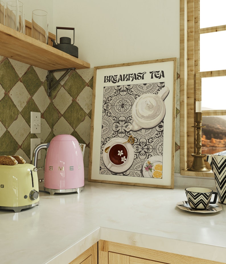 Puede incluir: Una impresi&oacute;n enmarcada con el texto "Breakfast Tea" en una fuente en blanco y negro. La impresi&oacute;n presenta una tetera blanca, una taza de t&eacute; blanca con un platillo y un plato blanco con limones sobre un fondo estampado en blanco y negro.