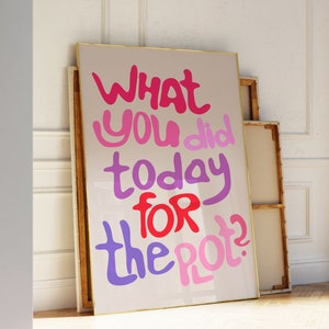 May include: A framed print with a pink, purple, and red text overlay that reads "What you did today for the pot?" The print is on a light beige background and has a gold frame.