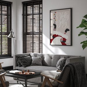 Puede incluir: Un sof&aacute; gris con cojines negros y una manta negra en una silla delante de &eacute;l. Una mesa de centro negra con una bandeja de vasos encima est&aacute; delante del sof&aacute;. Una impresi&oacute;n enmarcada con el texto "Holly Jolly" y un dibujo animado de Pap&aacute; Noel colgado boca abajo est&aacute; en la pared detr&aacute;s del sof&aacute;.