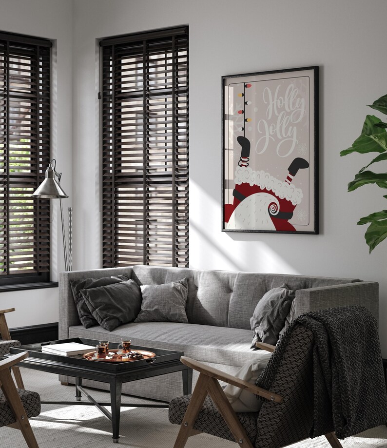 Puede incluir: Un sof&aacute; gris con cojines negros y una manta negra en una silla delante de &eacute;l. Una mesa de centro negra con una bandeja de vasos encima est&aacute; delante del sof&aacute;. Una impresi&oacute;n enmarcada con el texto "Holly Jolly" y un dibujo animado de Pap&aacute; Noel colgado boca abajo est&aacute; en la pared detr&aacute;s del sof&aacute;.